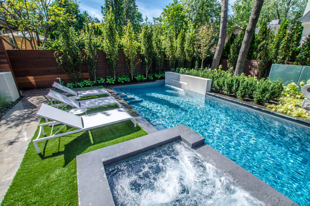 This is an example of a small contemporary back full sun garden for summer in Toronto with a water feature and natural stone paving.