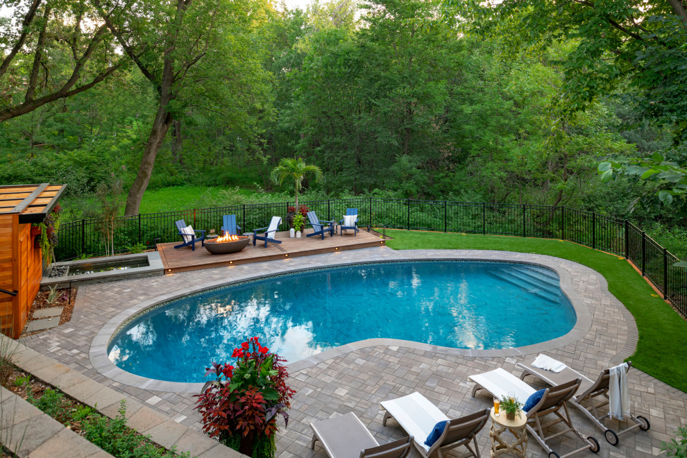 Foto de piscina de tamaño medio en patio trasero con adoquines de piedra natural