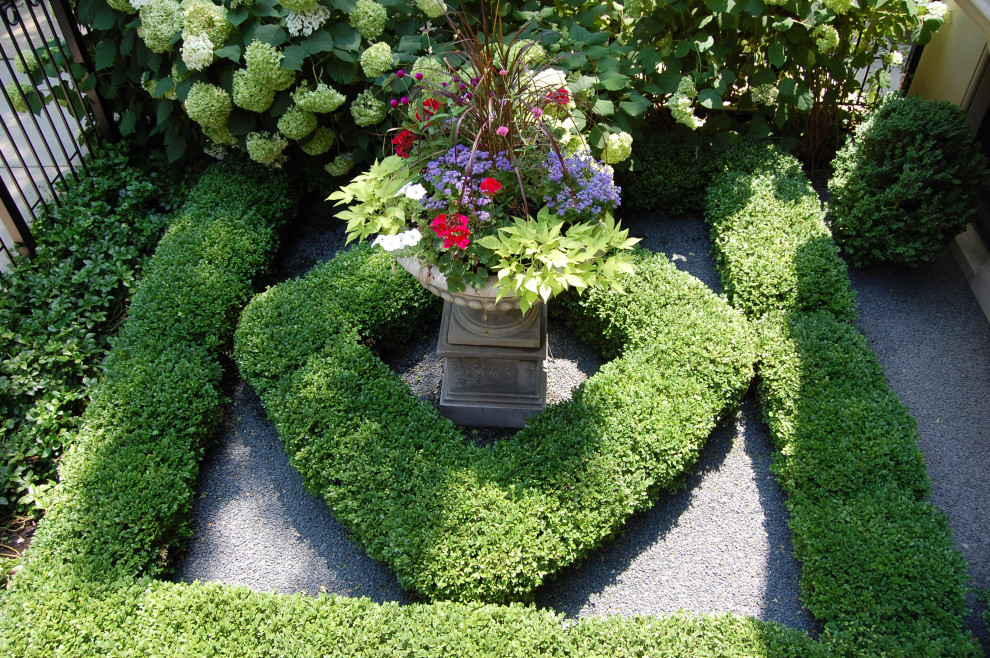 Cette image montre un petit jardin avant traditionnel l'été avec une exposition partiellement ombragée et un gravier de granite.