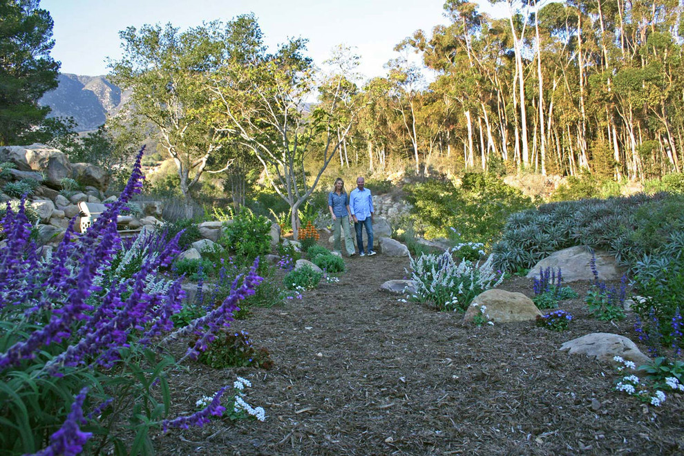 На фото: солнечный засухоустойчивый сад среднего размера на склоне в средиземноморском стиле с подпорной стенкой, хорошей освещенностью и мульчированием с