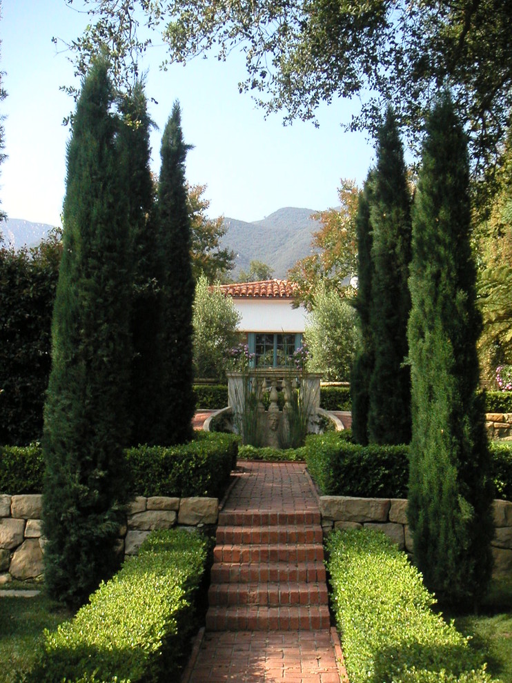 Exempel på en stor medelhavsstil trädgård, med en damm och marksten i tegel