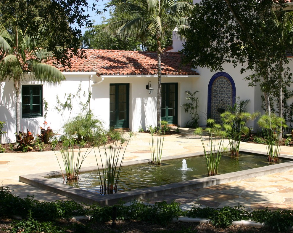 Idee per un ampio giardino formale mediterraneo dietro casa con fontane e pavimentazioni in pietra naturale