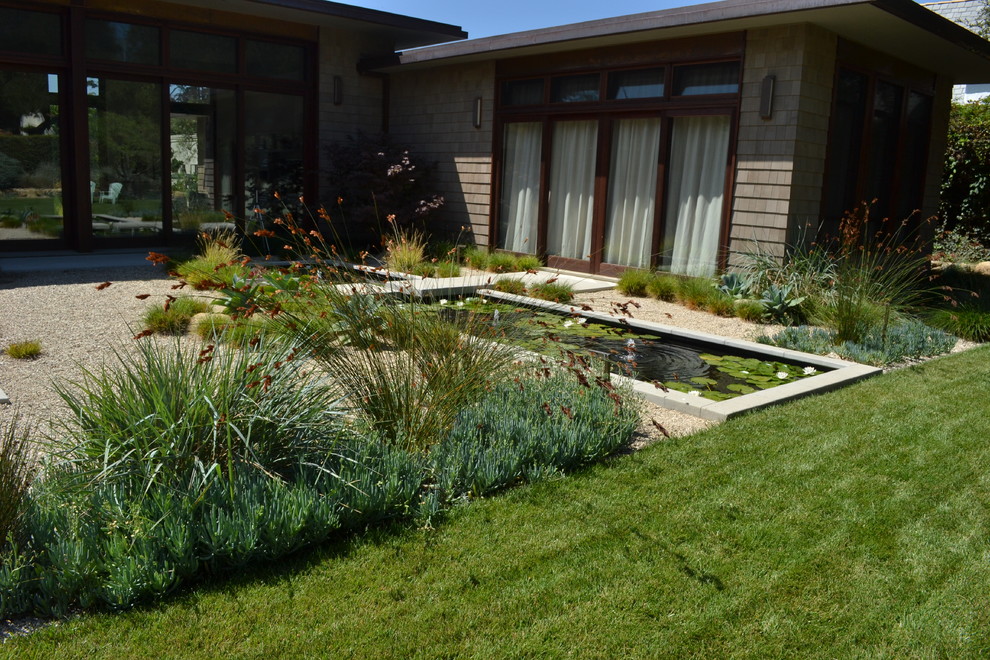 Ejemplo de jardín actual extra grande en patio trasero con fuente, exposición total al sol y adoquines de hormigón