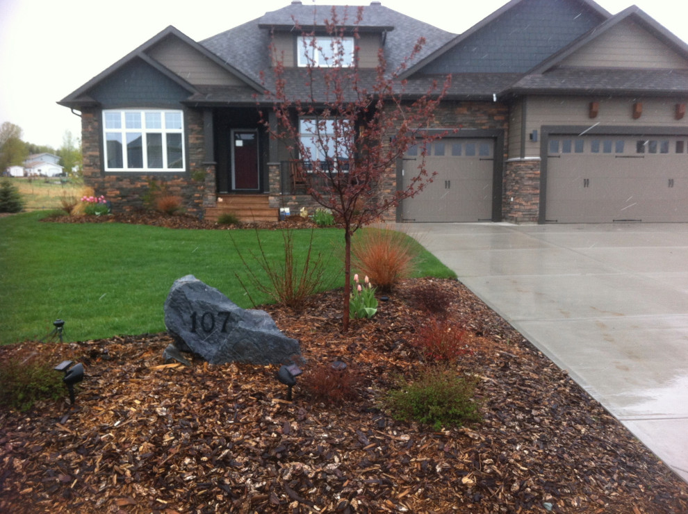 Medium sized traditional front formal garden in Calgary with a flowerbed and mulch.