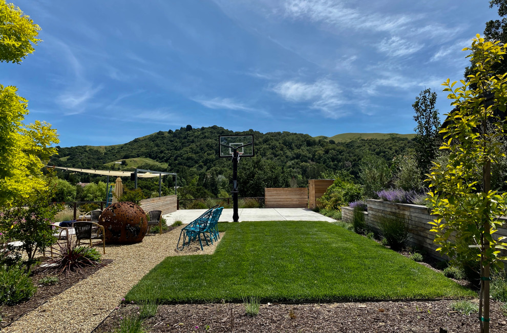 Photo of a large modern full sun backyard gravel and wood fence outdoor sport court in San Francisco with a fire pit.