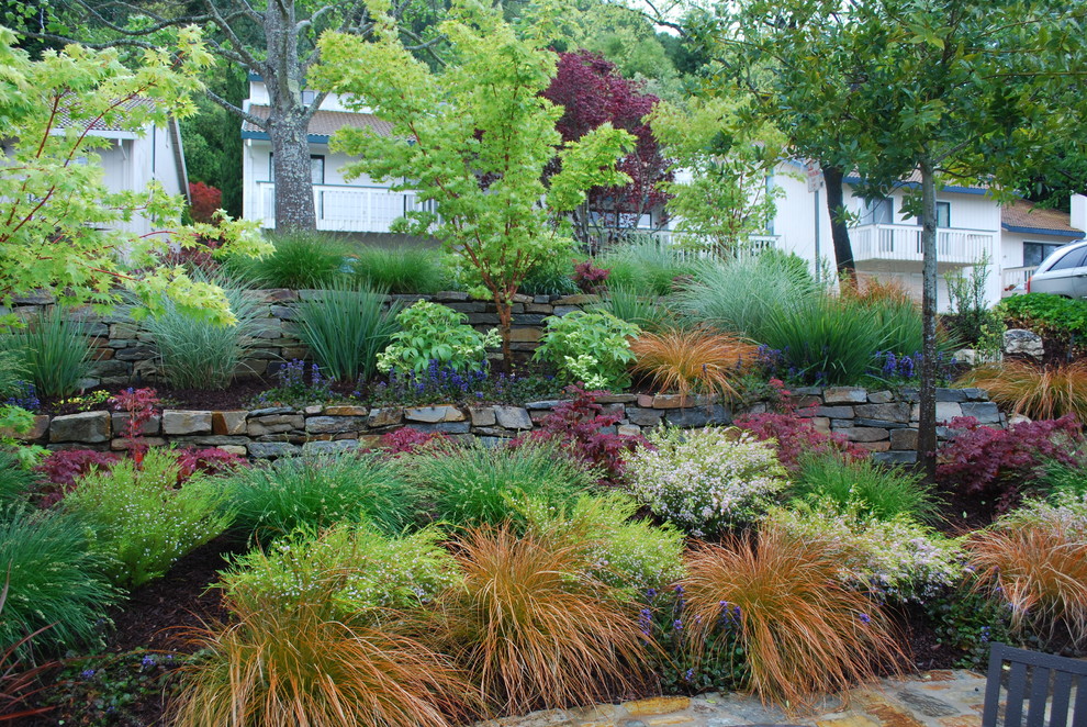 Cette image montre un petit jardin sur cour bohème au printemps avec un mur de soutènement, une exposition partiellement ombragée et des pavés en pierre naturelle.