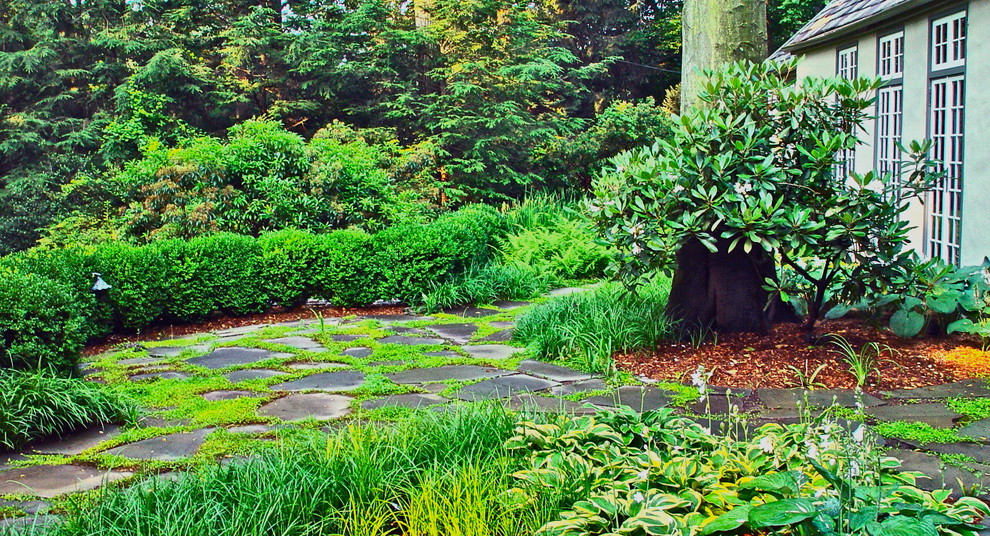 Exempel på en klassisk bakgård i skuggan, med naturstensplattor