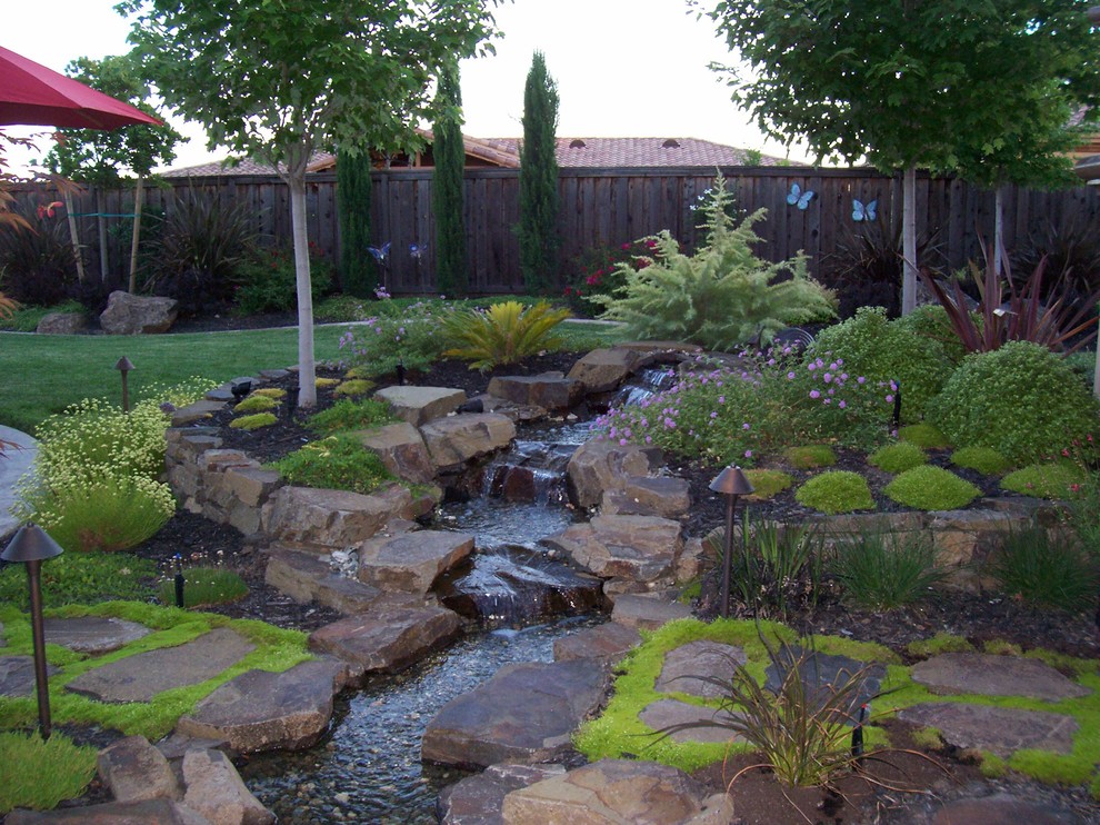 Photo of a large mediterranean full sun backyard stone water fountain landscape in Sacramento for summer.