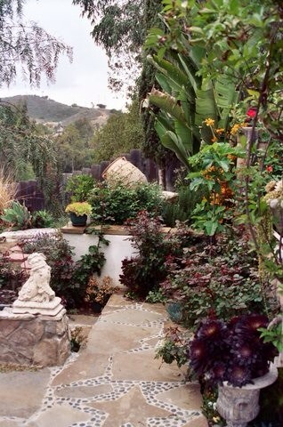 Geometrischer, Großer Mediterraner Gartenweg hinter dem Haus, im Sommer mit direkter Sonneneinstrahlung, Natursteinplatten und Steinzaun in San Diego