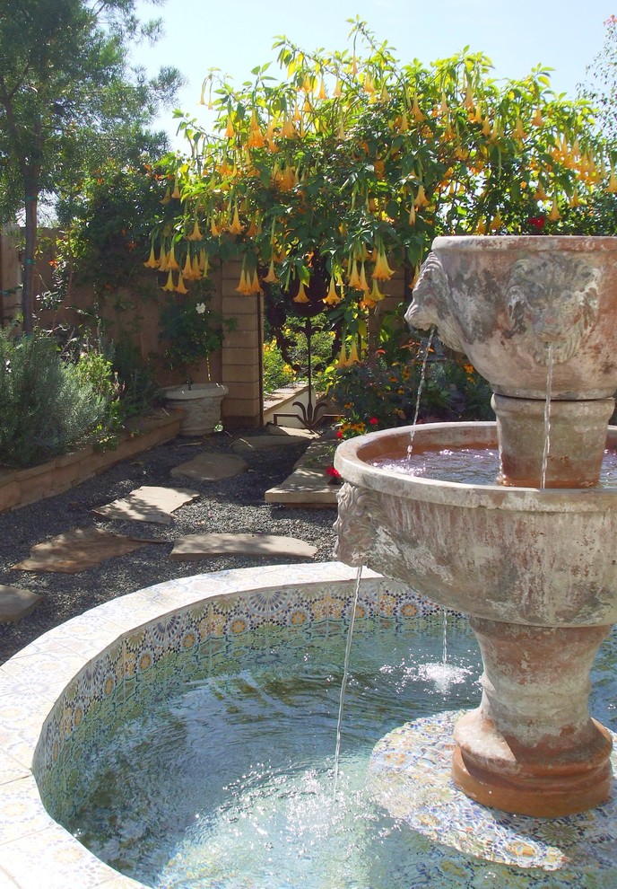 Imagen de jardín mediterráneo extra grande en verano en patio trasero con jardín francés, fuente, exposición total al sol y gravilla