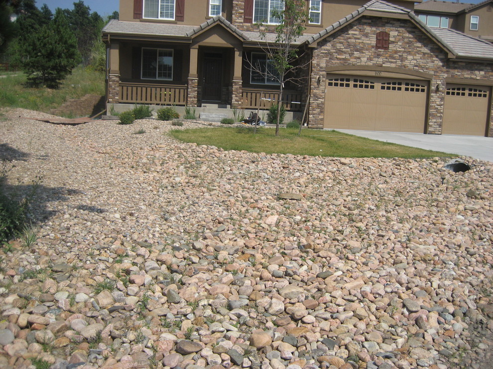 This is an example of a large rustic front full sun garden in Denver with natural stone paving.