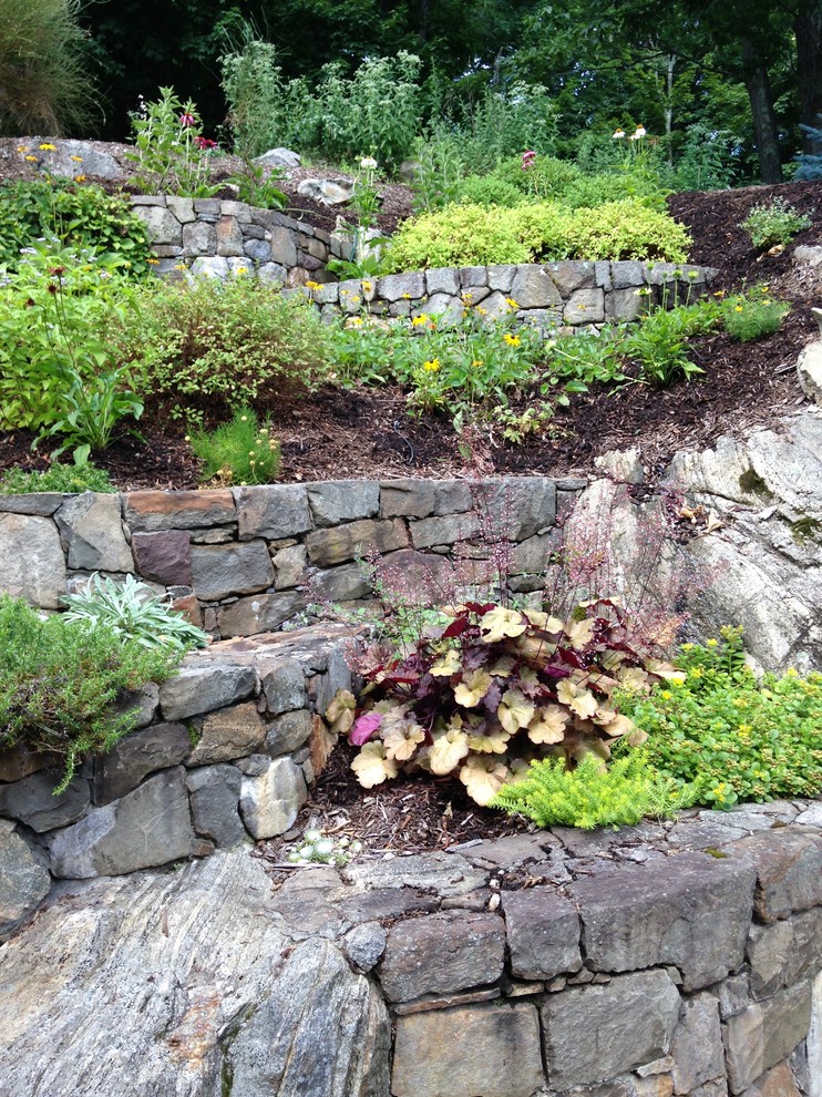This is an example of a large rustic sloped formal garden for summer in New York with natural stone paving.