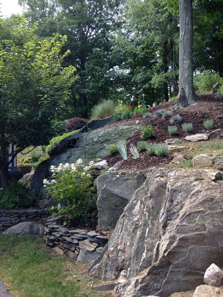 This is an example of a large rustic sloped full sun garden for summer in New York with a living wall and natural stone paving.