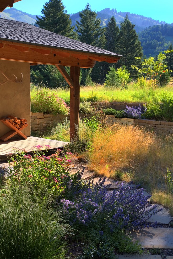 Inspiration för trädgårdar i delvis sol framför huset, med en stödmur och naturstensplattor