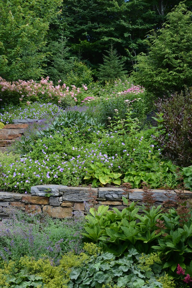 Inspiration for a large contemporary sloped full sun garden in Burlington with a retaining wall.