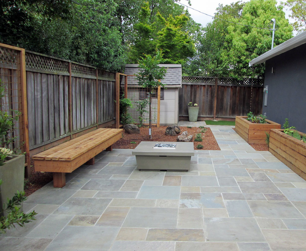 Immagine di un patio o portico moderno di medie dimensioni e dietro casa con un focolare e pavimentazioni in pietra naturale