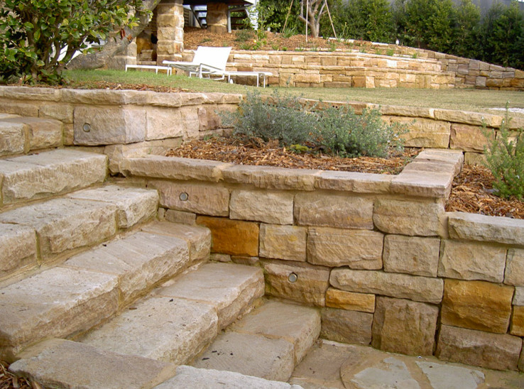 Ejemplo de jardín clásico grande en patio trasero con muro de contención, exposición reducida al sol y adoquines de piedra natural