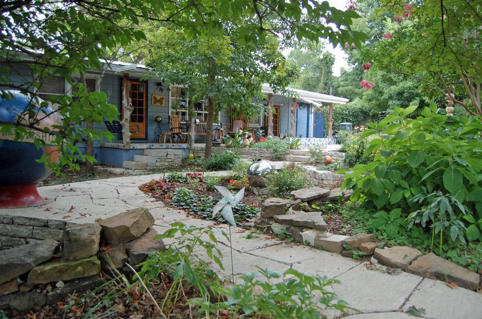 Exempel på en mellanstor eklektisk trädgård framför huset, med en trädgårdsgång och naturstensplattor
