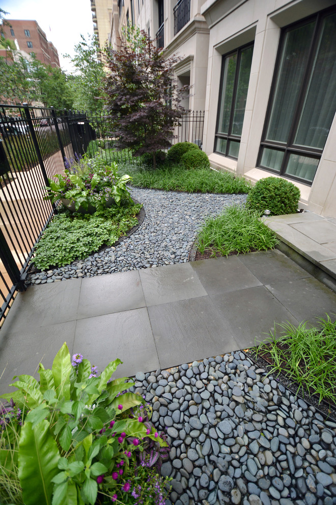 This is an example of a medium sized modern front formal partial sun garden in Chicago with a garden path and natural stone paving.