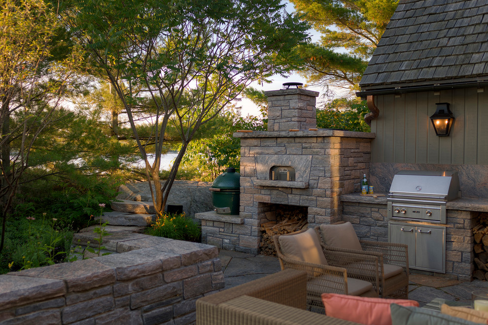 Cette photo montre une terrasse craftsman avec une cheminée, une cour et des pavés en pierre naturelle.