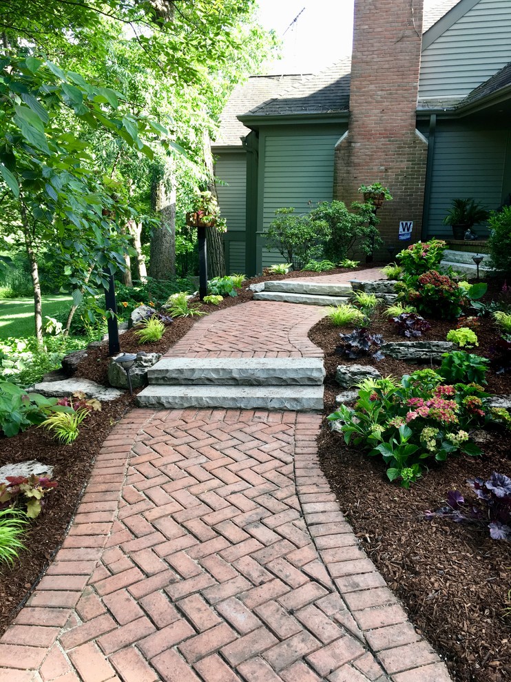 Immagine di un giardino formale tradizionale esposto a mezz'ombra di medie dimensioni e davanti casa in estate con un ingresso o sentiero e pavimentazioni in mattoni