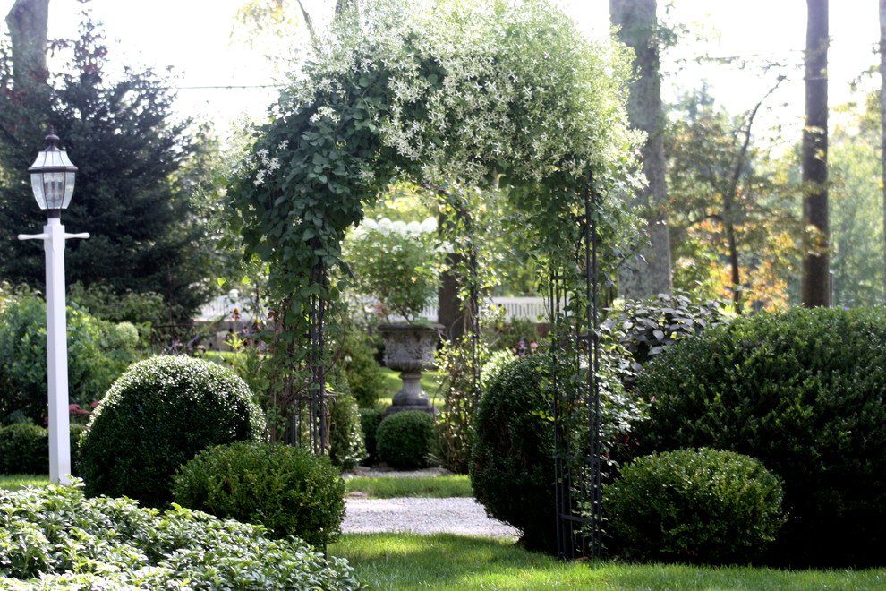 This is an example of a large traditional full sun front yard gravel landscaping in New York.