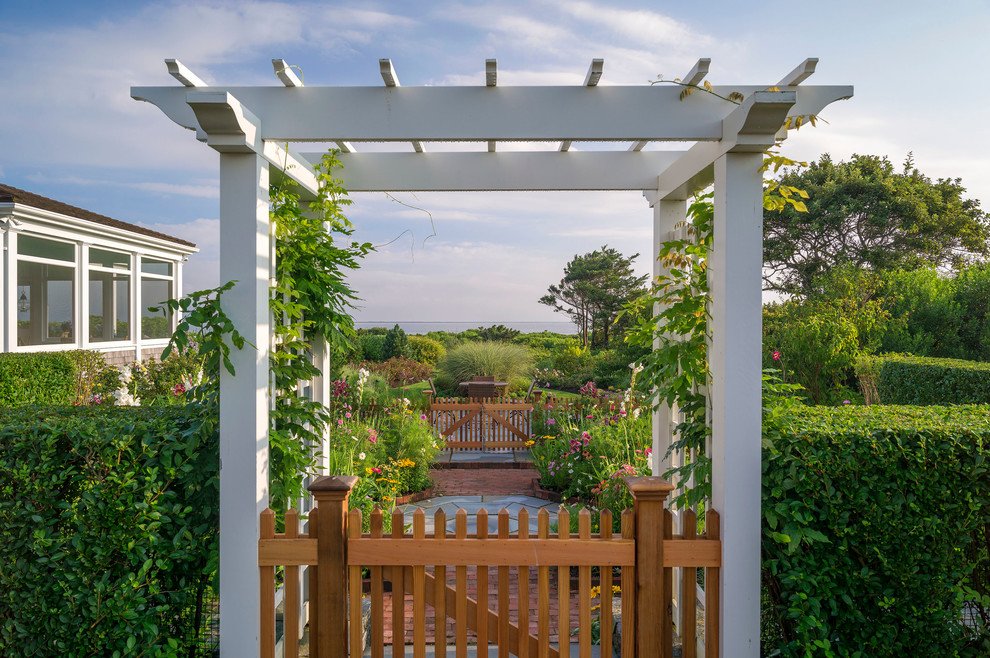 Immagine di un grande giardino formale stile marinaro esposto in pieno sole dietro casa con un ingresso o sentiero e pavimentazioni in mattoni