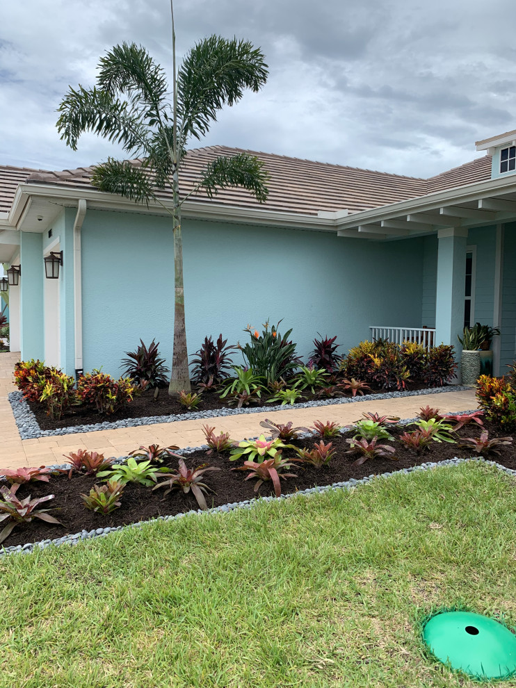 This is an example of a mid-sized tropical rock and full sun front yard river rock formal garden in Miami.