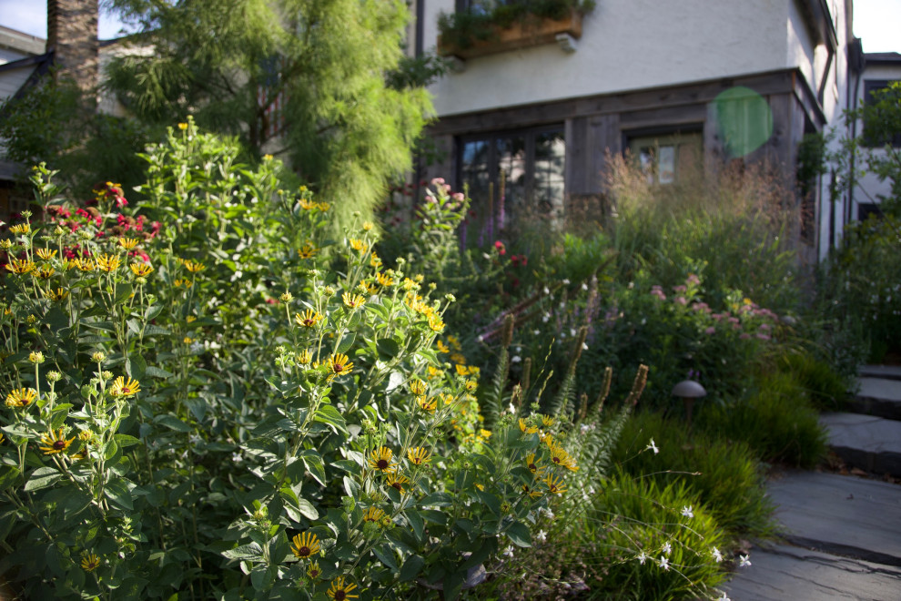 На фото: маленький солнечный участок и сад на переднем дворе в стиле рустика с клумбами, хорошей освещенностью и покрытием из каменной брусчатки для на участке и в саду