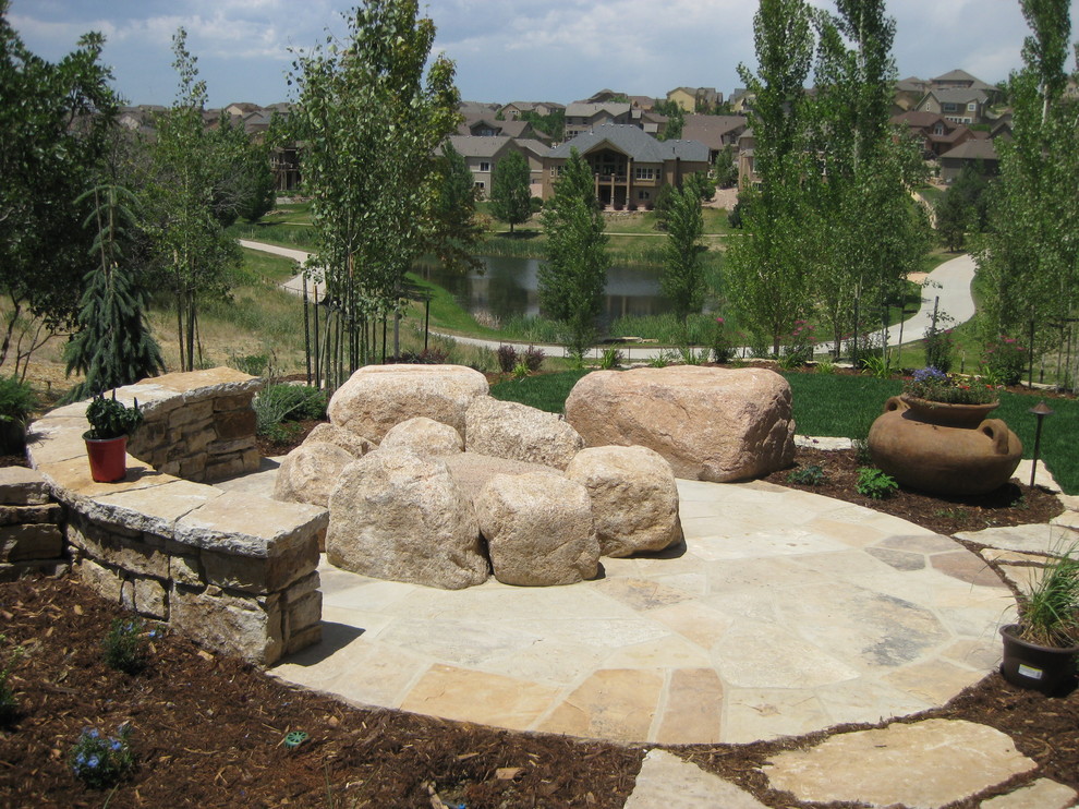 Medium sized back xeriscape partial sun garden for summer in Denver with a fire feature and natural stone paving.