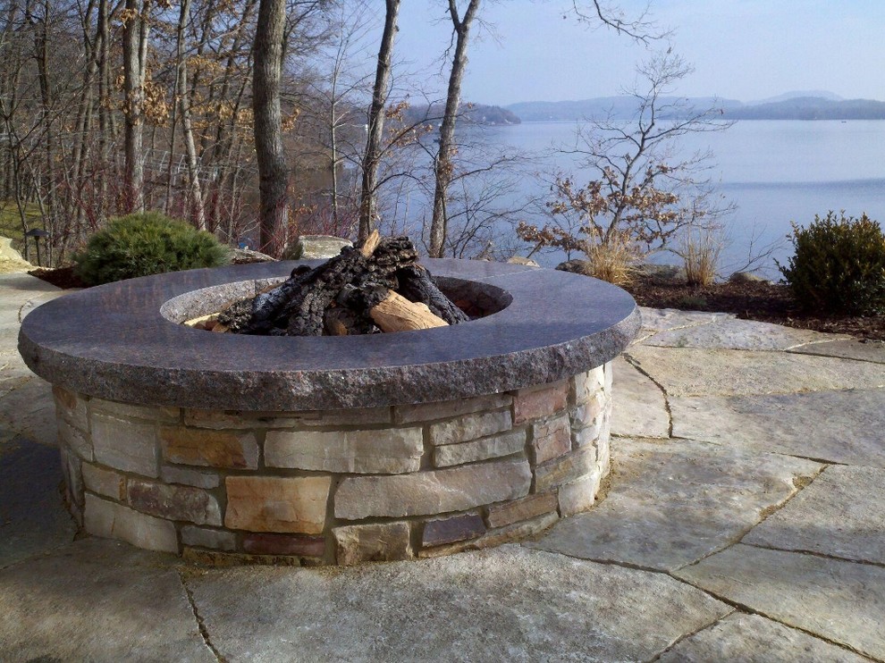 Photo of a medium sized rustic sloped partial sun garden for summer in Milwaukee with a fire feature and natural stone paving.