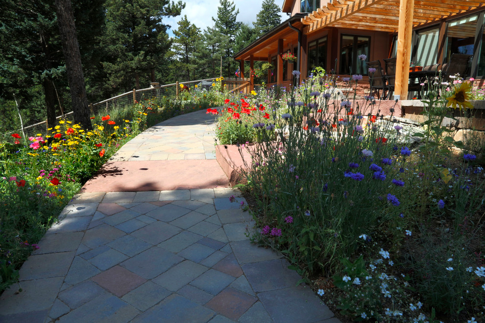 This is an example of a large rustic partial sun backyard stone landscaping in Denver.
