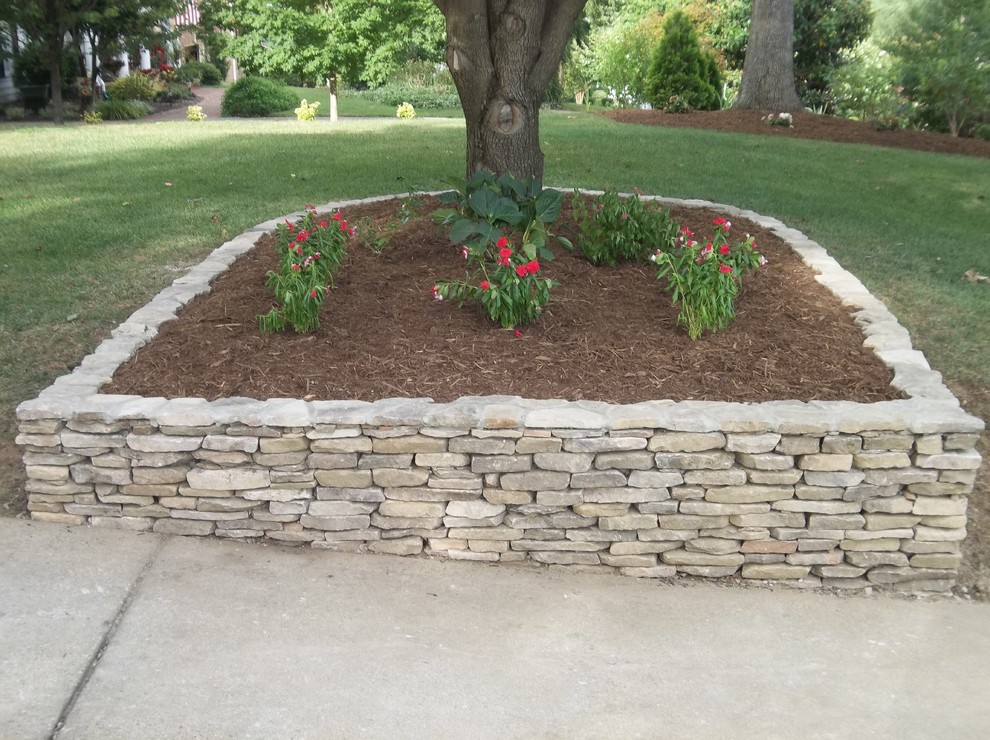 Photo of a medium sized contemporary front driveway garden in Raleigh with a retaining wall.