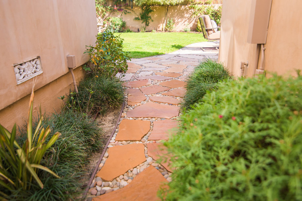 Photo of a small back formal full sun garden for spring in Los Angeles with a garden path and natural stone paving.
