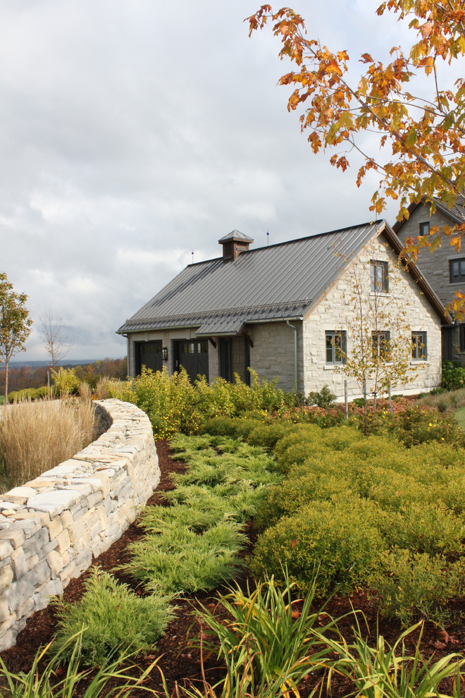 Photo of a farmhouse full sun garden in Toronto with a retaining wall.