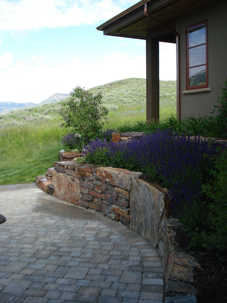 Small classic back formal full sun garden for spring in Boise with a fire feature and natural stone paving.