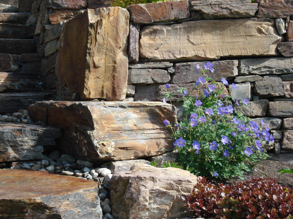Foto di un piccolo giardino formale tradizionale esposto in pieno sole dietro casa in primavera con un focolare e pavimentazioni in pietra naturale