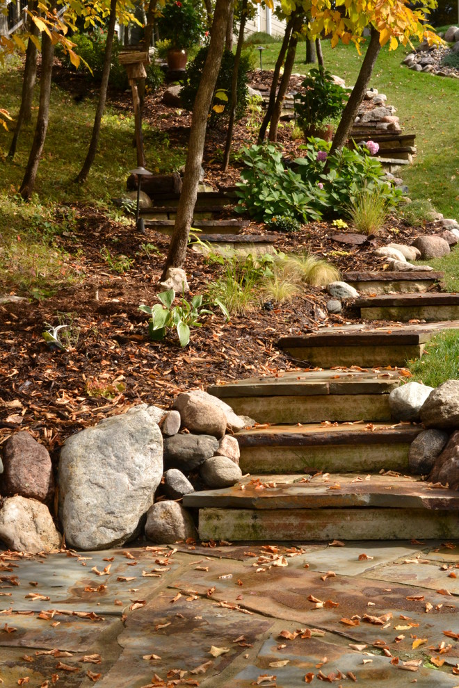 This is an example of a large traditional partial sun hillside stone garden path in Other.