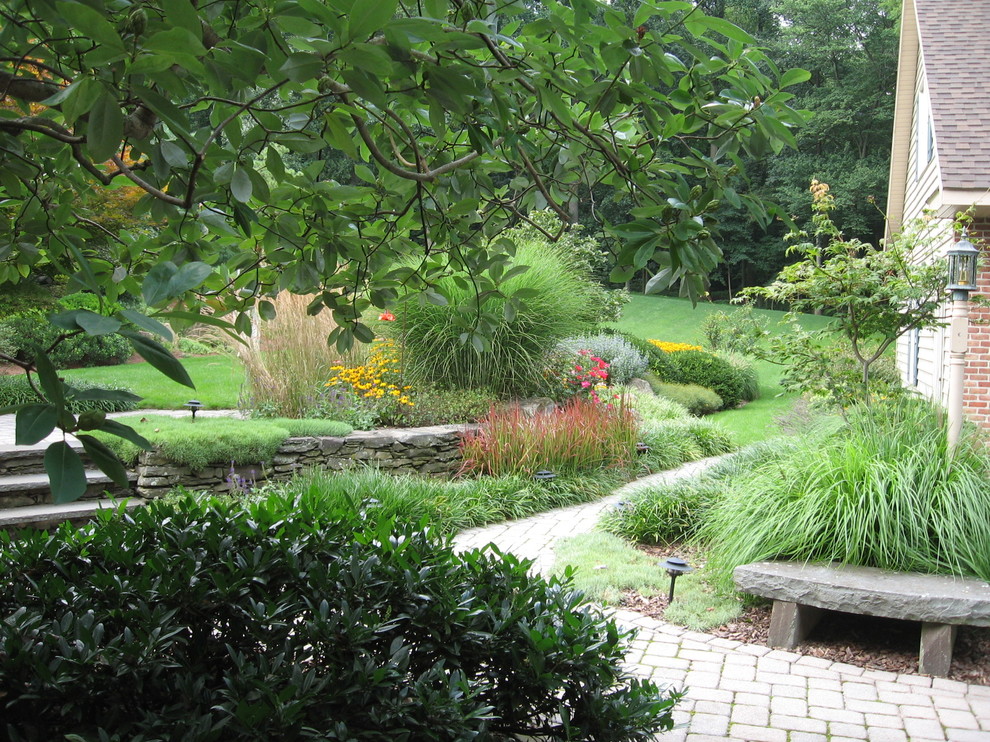 Cette image montre un grand jardin à la française arrière traditionnel l'été avec une exposition ensoleillée et des pavés en brique.