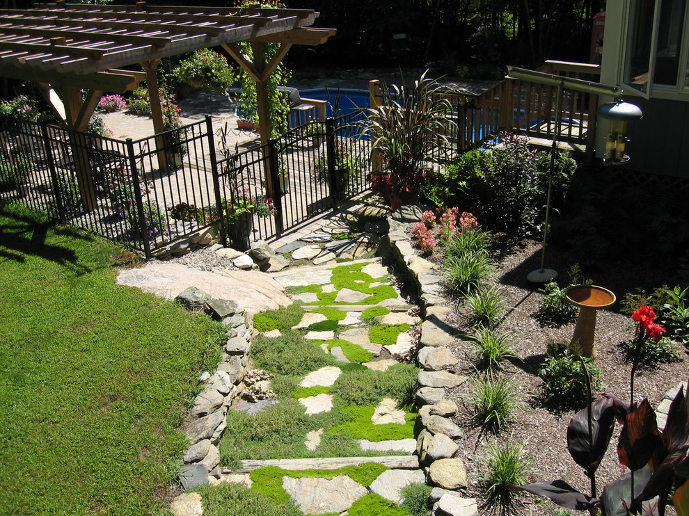 Foto di un grande giardino classico esposto in pieno sole dietro casa in estate con un ingresso o sentiero e pavimentazioni in pietra naturale