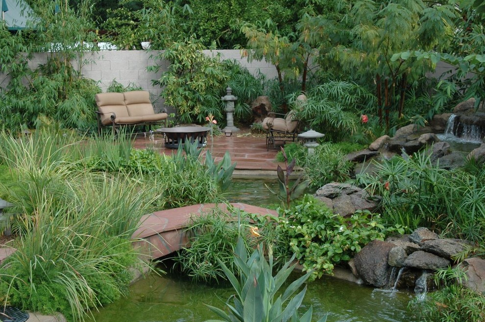 Inspiration for a large world-inspired front formal partial sun garden in Phoenix with a water feature and natural stone paving.