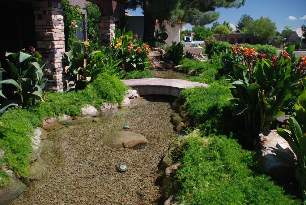 Imagen de jardín exótico grande en patio delantero con fuente, jardín francés, exposición parcial al sol y adoquines de piedra natural