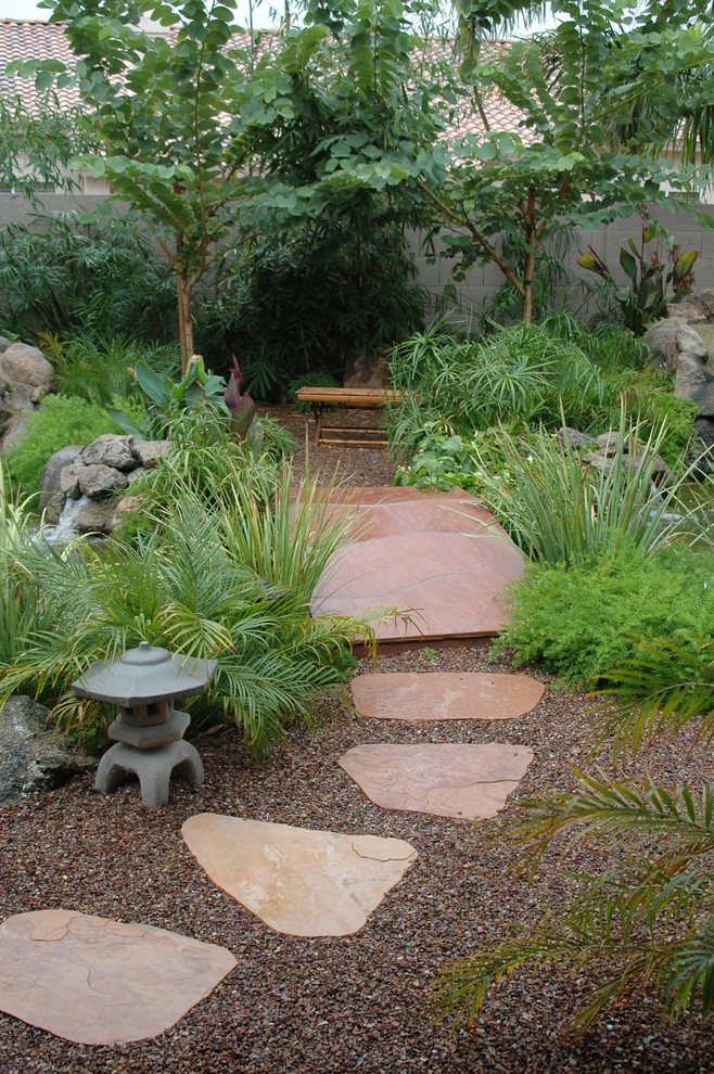 Стильный дизайн: большой регулярный сад на переднем дворе в восточном стиле с садовой дорожкой или калиткой, полуденной тенью и покрытием из каменной брусчатки - последний тренд