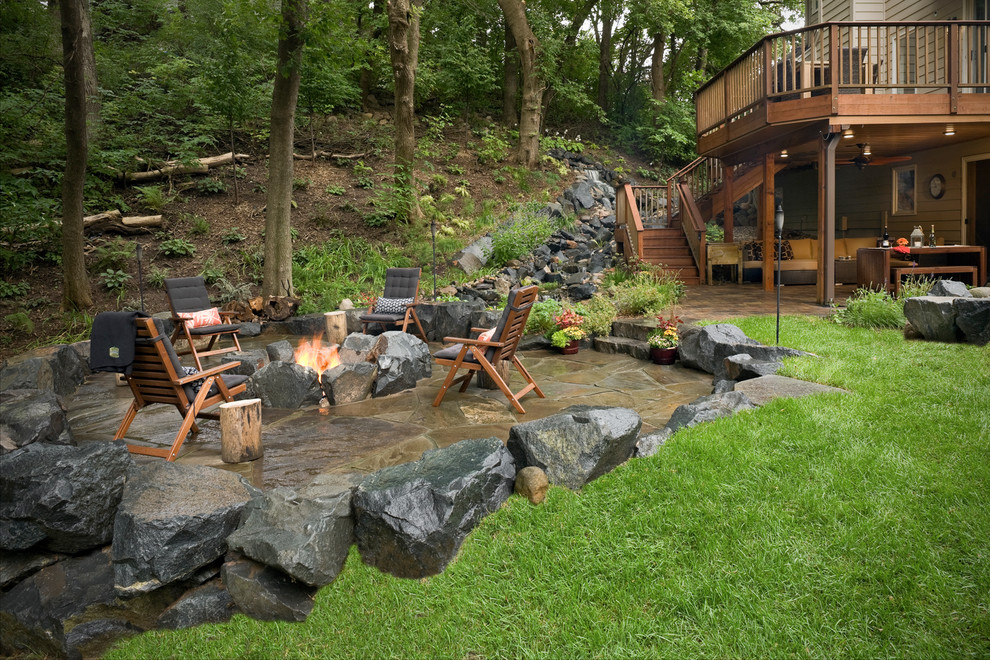 Photo of a large rustic drought-tolerant backyard stone landscaping in Minneapolis.