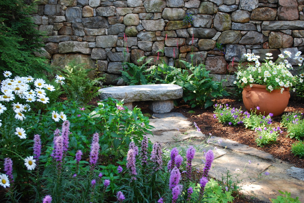 Foto de jardín clásico de tamaño medio en verano en patio delantero con muro de contención, adoquines de piedra natural y exposición reducida al sol