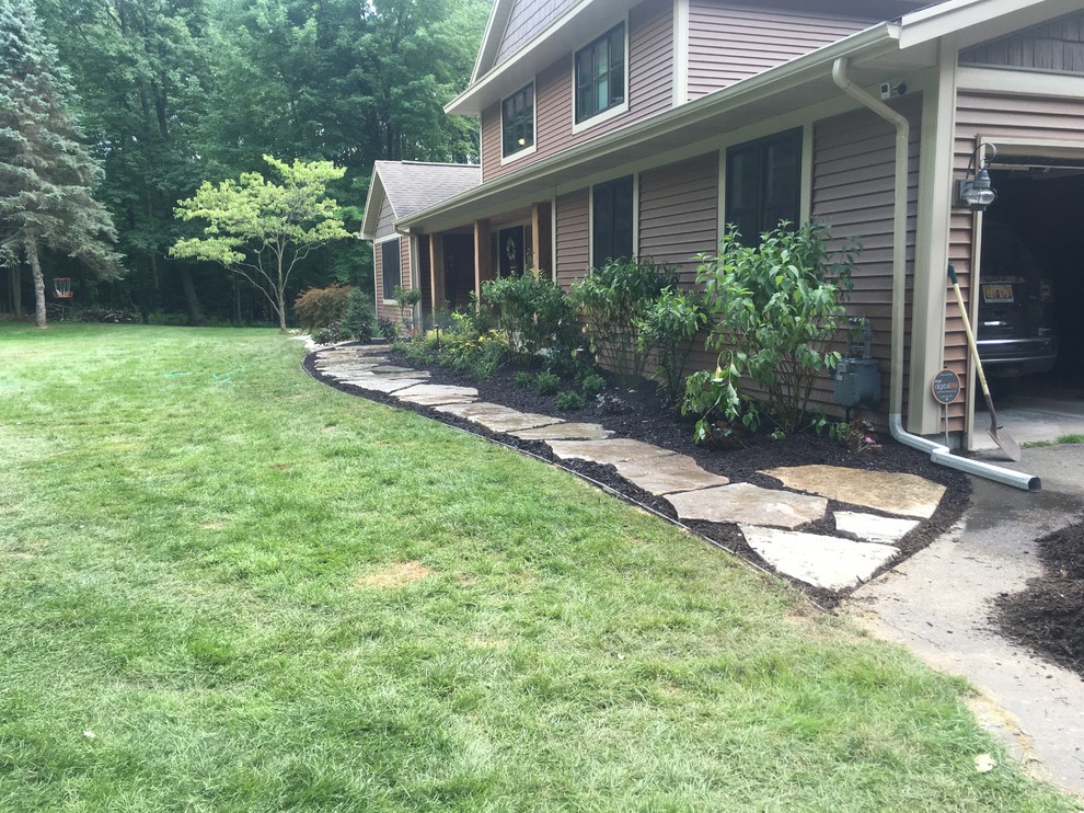 This is an example of a large rustic back partial sun garden in Grand Rapids with a garden path and natural stone paving.