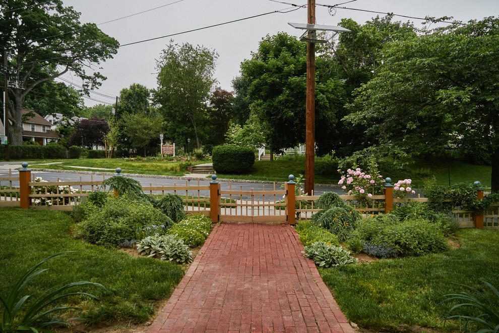 Cette image montre un jardin avant traditionnel de taille moyenne et au printemps avec une exposition ensoleillée et des pavés en brique.