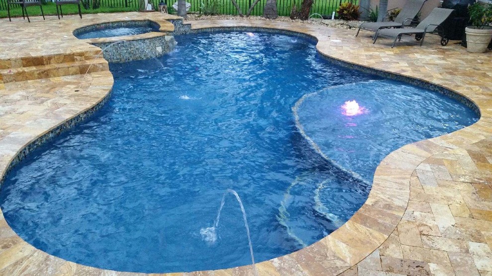 Foto di una grande piscina chic dietro casa con fontane e pavimentazioni in pietra naturale