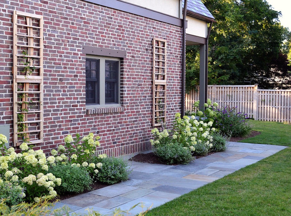 Пример оригинального дизайна: большой регулярный сад на боковом дворе в классическом стиле с садовой дорожкой или калиткой, полуденной тенью и покрытием из каменной брусчатки