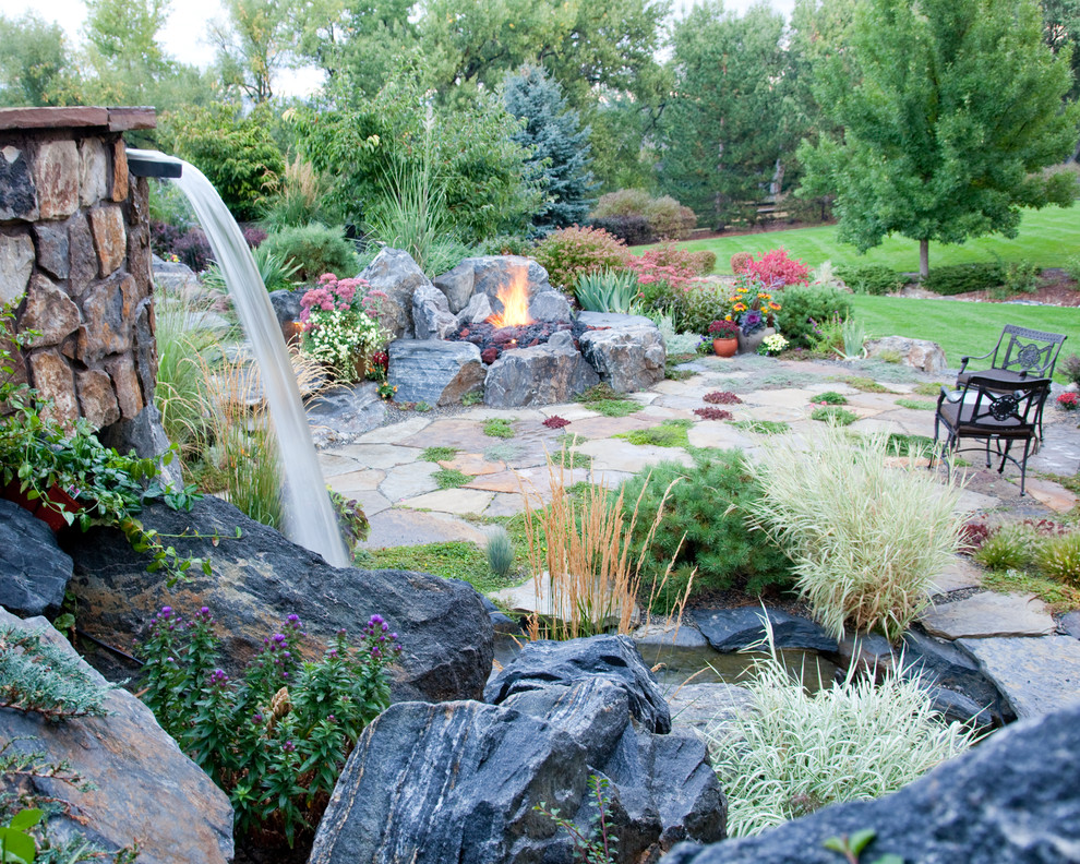 Foto de jardín rústico de tamaño medio en patio trasero con jardín francés, fuente y adoquines de piedra natural